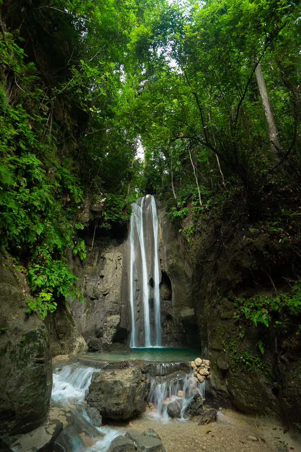 a waterfall in the middle of a lush green forest.