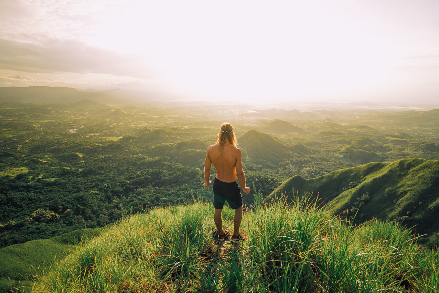 a man standing on top of a lush green hillside.