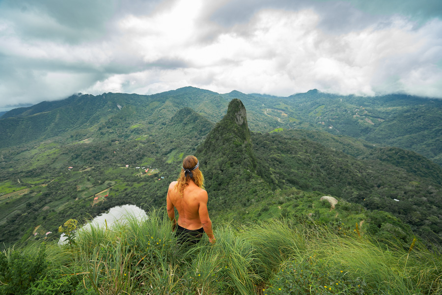 a man standing on top of a lush green hillside.