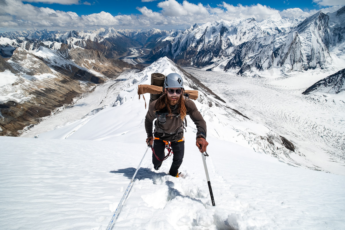 a man hiking up a snowy mountain with skis and poles