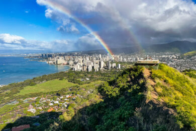 a rainbow is seen over a city on a hill