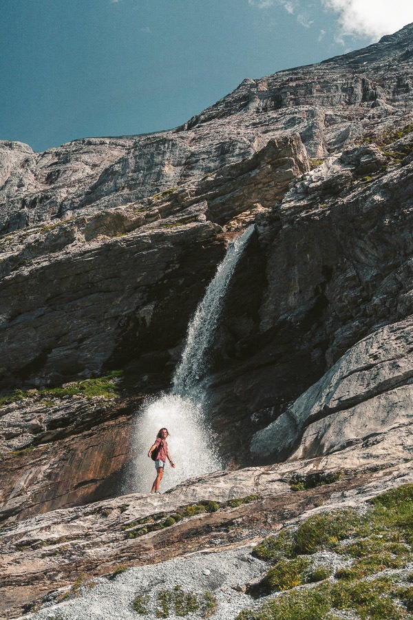 a man is standing on a rock near a waterfall.