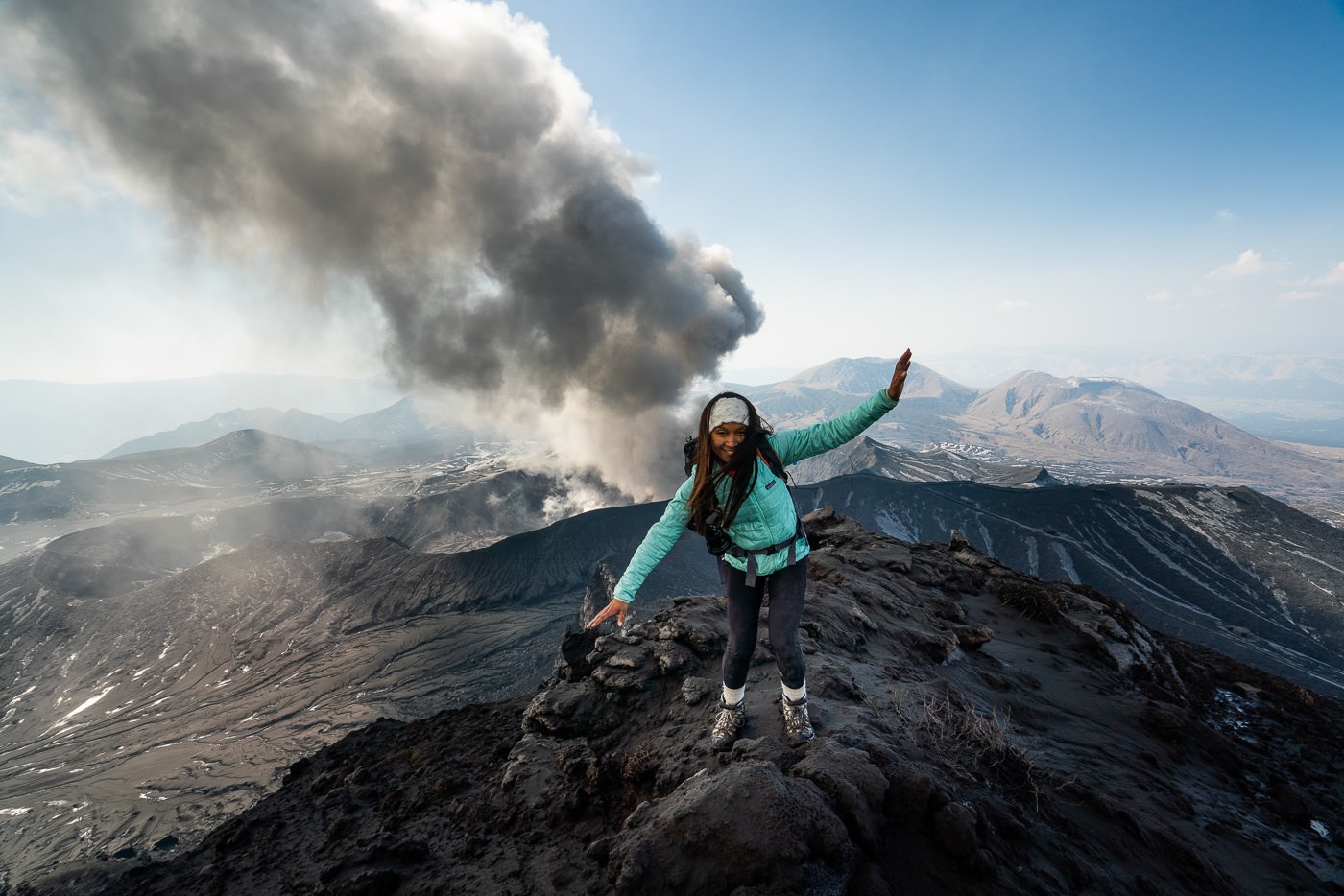 a woman standing on top of a mountain with smoke coming out of her mouth.