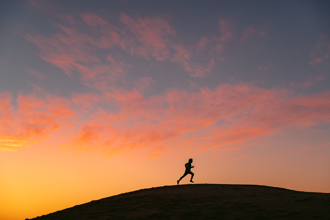 a person is running on a hill at sunset.