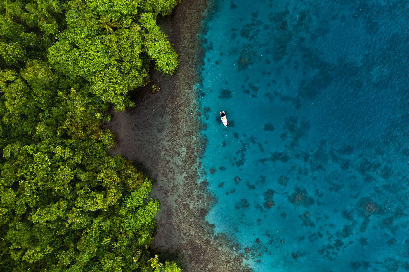 an aerial view of a boat in the middle of a body of water.