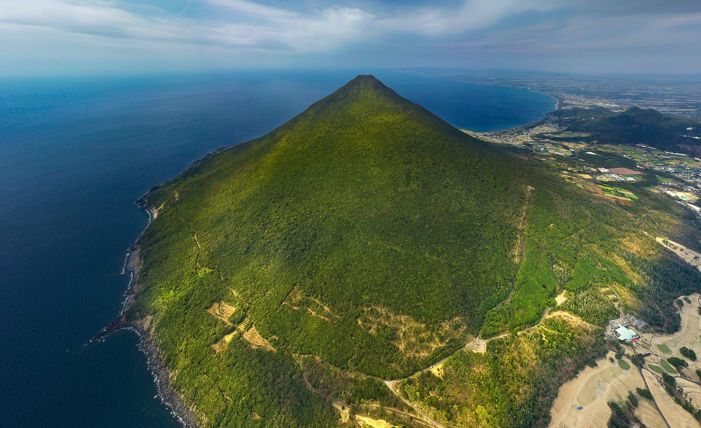 an aerial view of an island with a mountain in the background.