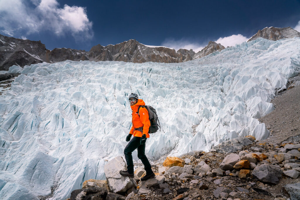 a man in an orange jacket standing on a rocky mountain