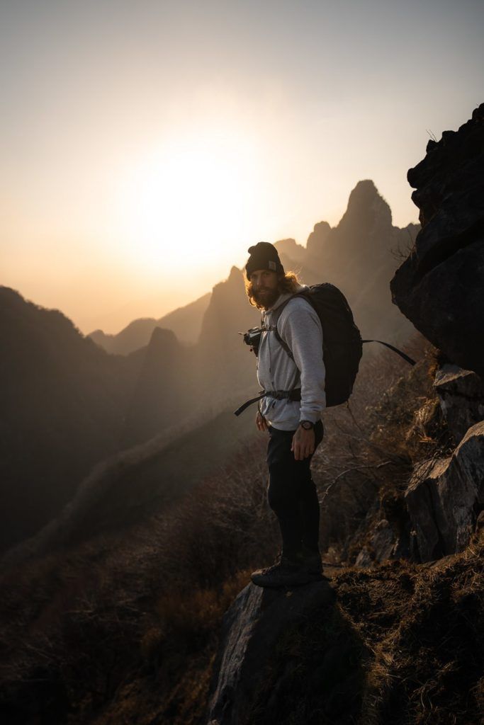 a man with a backpack standing on top of a mountain.