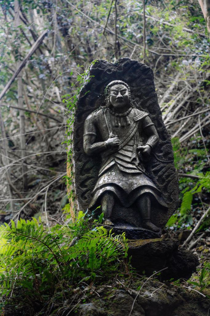 a statue of an angel in the woods.