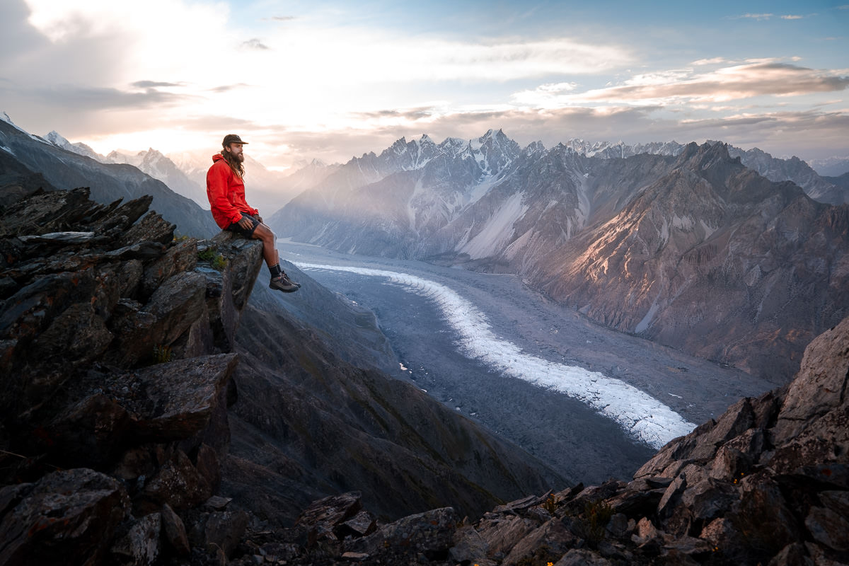 a man sitting on top of a mountain next to Passu Glacier
