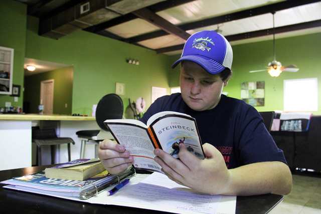 Cody Beck reads a book that was assigned by his teacher at Grenada Middle School. Since April, Cody has been on a “homebound” program due to behavior, where he does his work at home and meets with a teacher for four hours each week for instruction. (Photo by Jackie Mader)