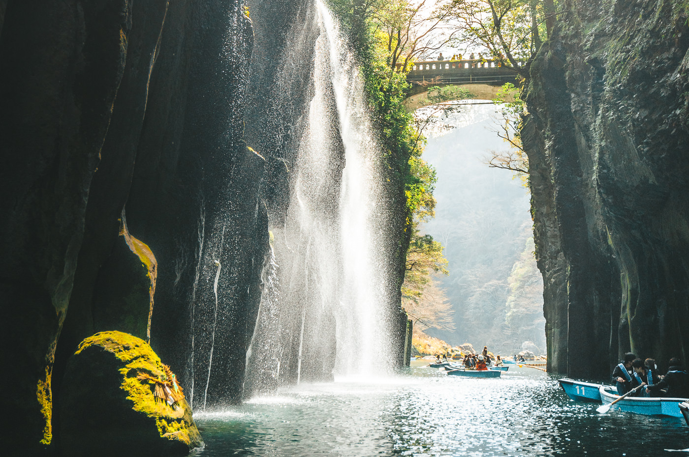 a group of people on a boat in front of a waterfall.