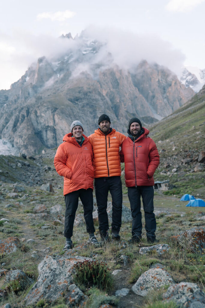 three men standing in front of a mountain