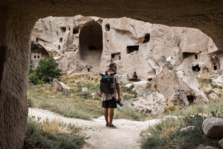 a man with a backpack standing in a cave.